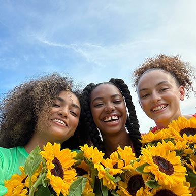 A sharp and vibrant selfie of three people holding yellow flowers, taken with the TrueDepth camera.